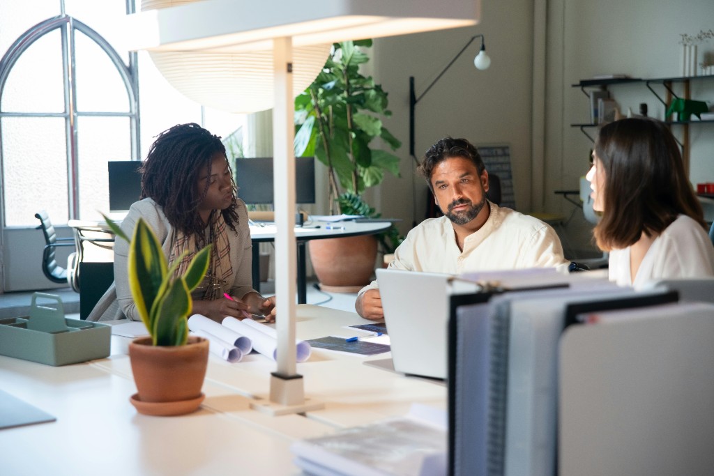 Professionnels autour d’un bureau, échange collaboratif dans un bureau lumineux.